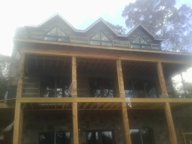 Dormers and porch framing on a large log home under construction — Roof Coating work by our crew in Taylors Falls