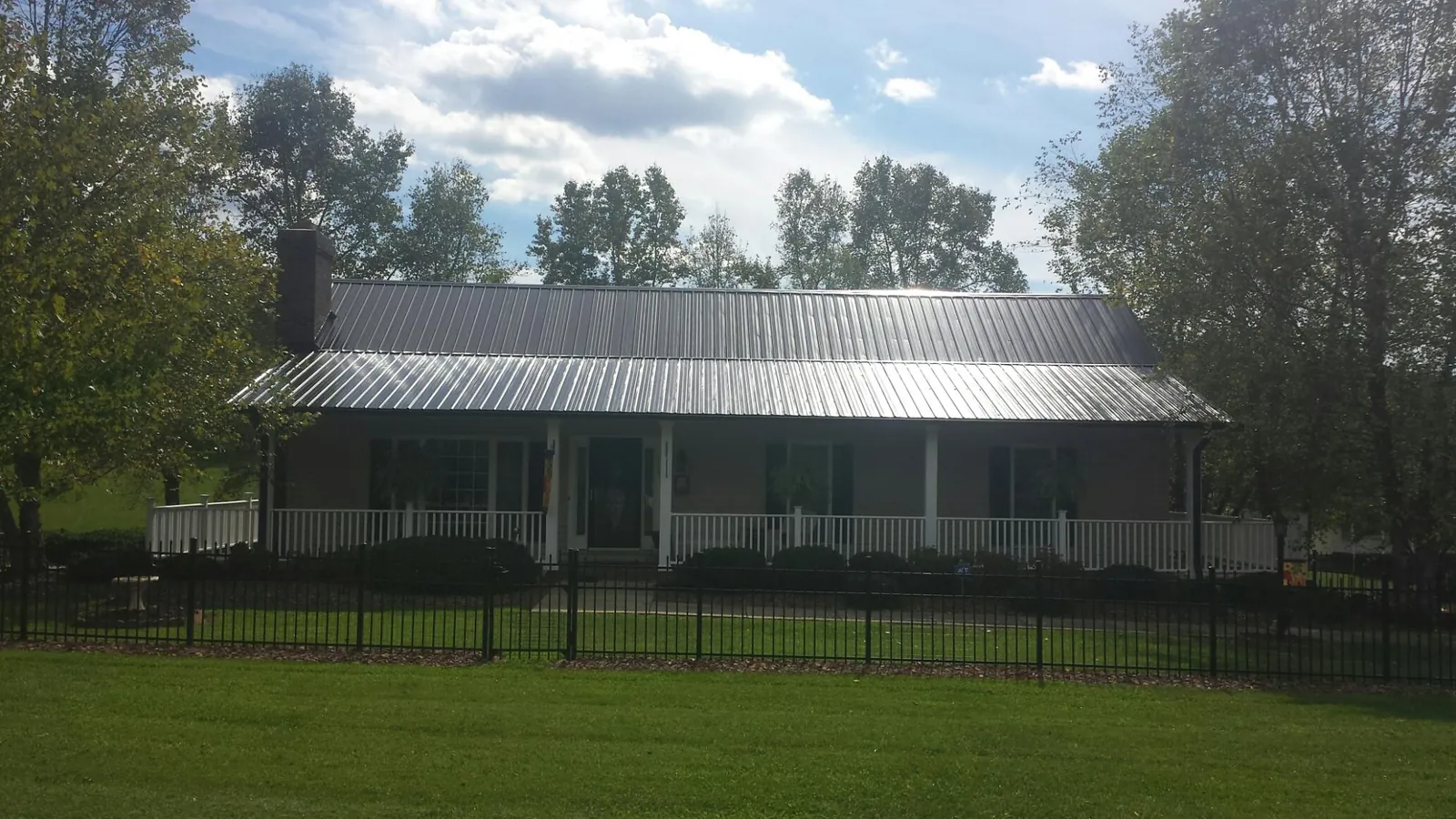 Gray metal roof on a brick ranch with a full width front porch — Gutter Guard Installation work by our crew in Taylors Falls
