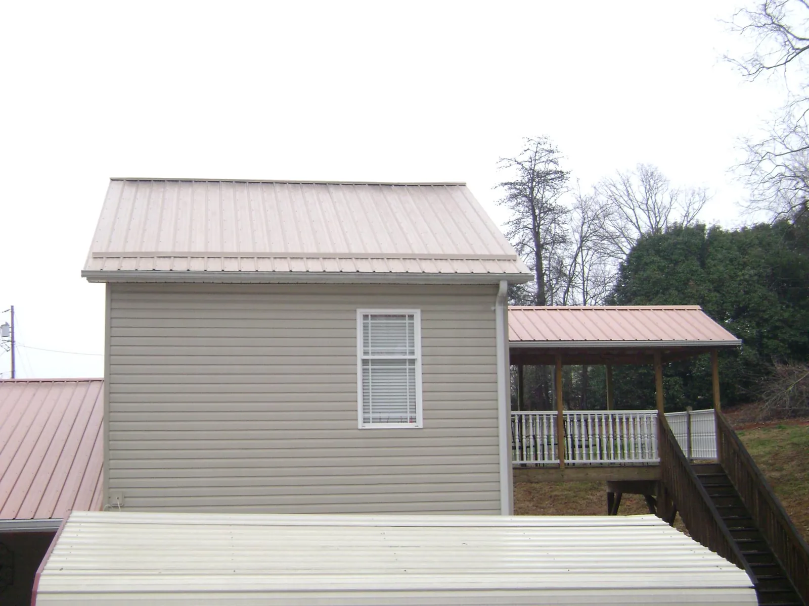 Tan metal roofs on a two story addition and attached porch, from a Roof Replacement job in Taylors Falls
